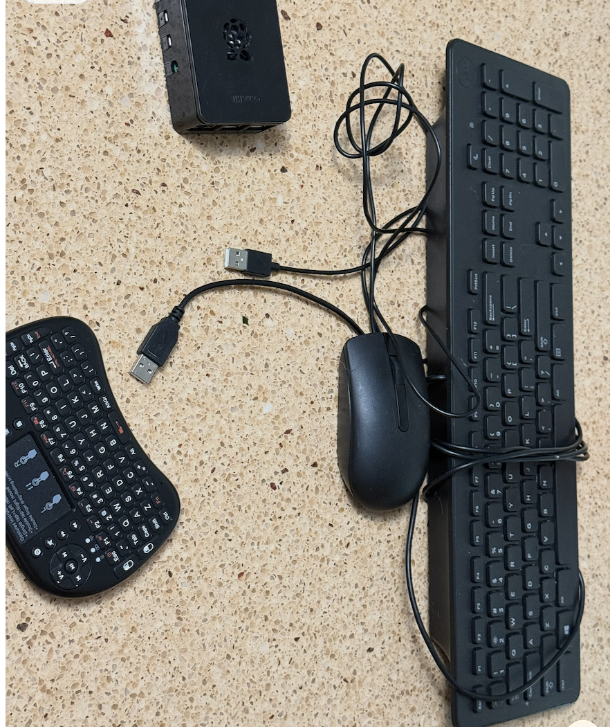 Left: Rii mini wireless keyboard. Right: the full-size keyboard we kept tripping over. Top: the Pi running the whole stack. Pi 4 case, full-size keyboard + mouse, and the Rii mini wireless keyboard with built-in touchpad